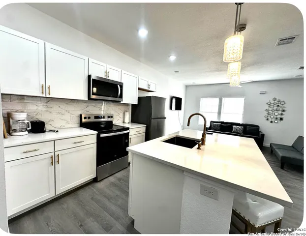 a kitchen with kitchen island granite countertop a sink stainless steel appliances and white cabinets