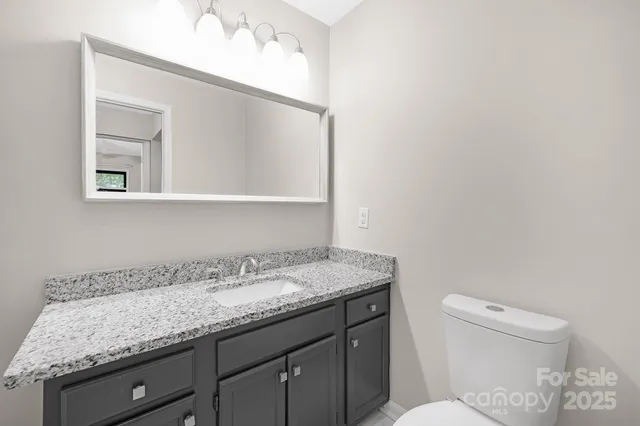 a bathroom with a granite countertop sink a toilet and mirror