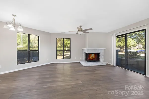 a view of an empty room with wooden floor fireplace and a window