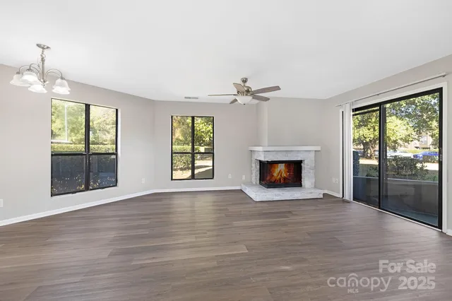 a view of an empty room with wooden floor fireplace and a window