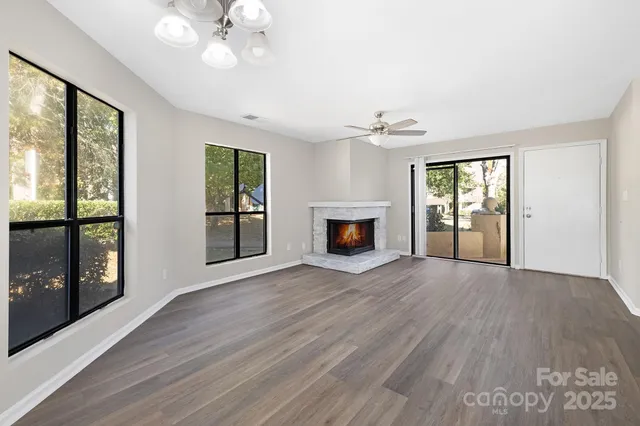 an empty room with wooden floor fan and windows