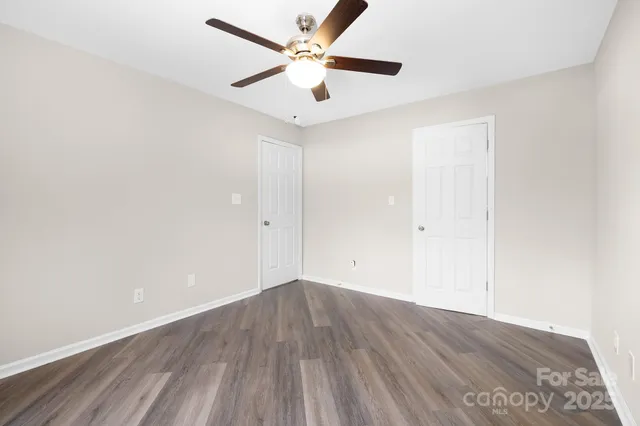 an empty room with wooden floor and a ceiling fan