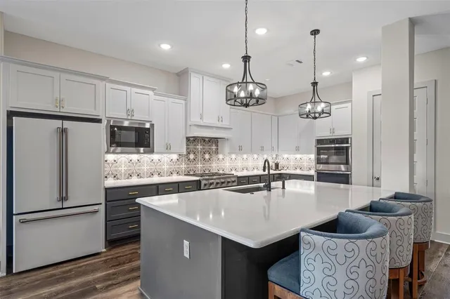 a kitchen with granite countertop a sink a center island stainless steel appliances and cabinets