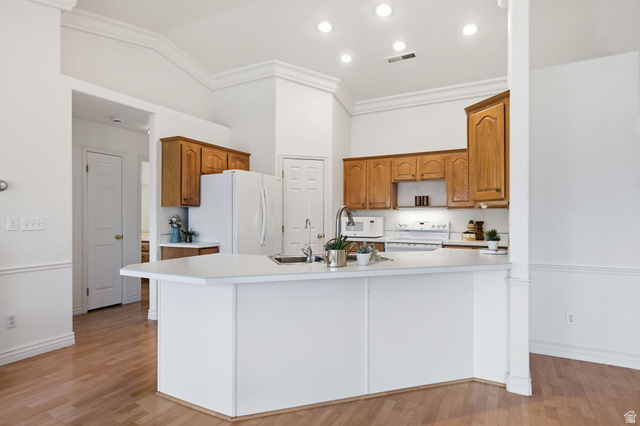 805 South River Road, Unit 70 St. George, UT 84790 - Photo 12 of 38 Kitchen featuring wood-finish flooring, white cabinetry, a kitchen island with sink, white appliances, and recessed lighting