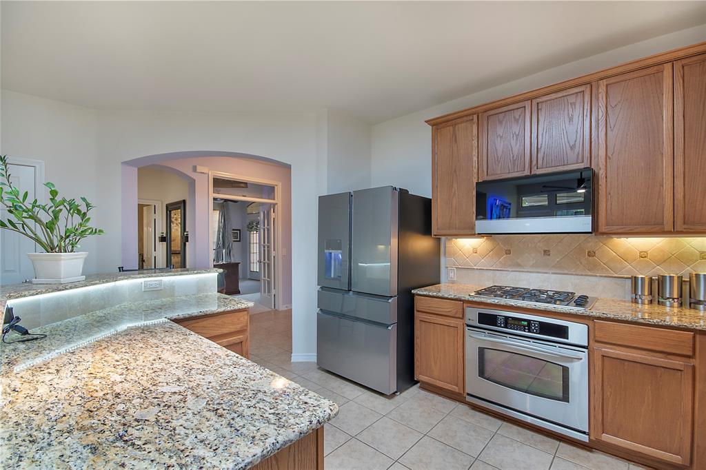 11601 Forestbrook Drive Frisco, TX 75035 - Photo 10 of 40 a kitchen with stainless steel appliances granite countertop a stove a sink and a refrigerator