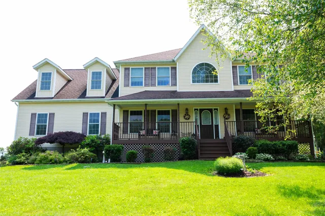 a view of a white house with a big yard and potted plants and a large tree