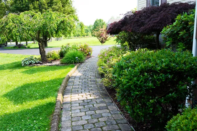 a view of a brick house with a big yard and large trees