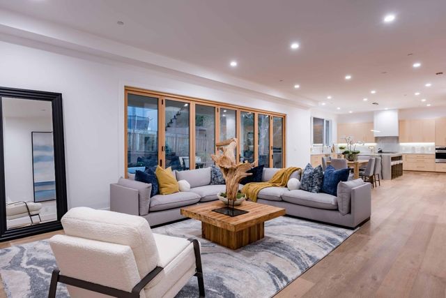 a living room with furniture kitchen view and a large window