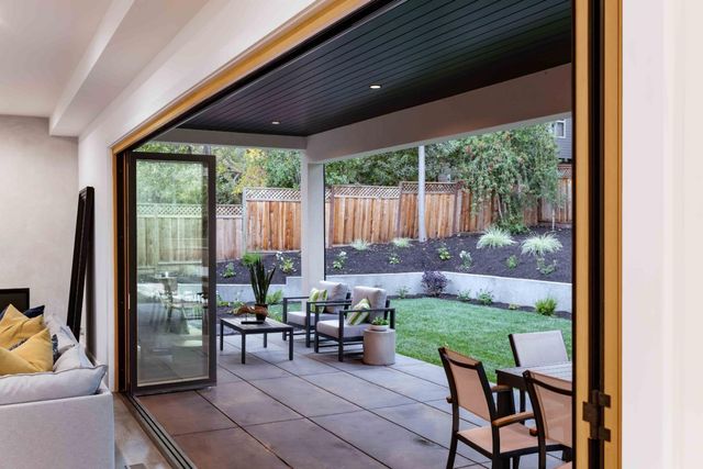 a view of a patio with table and chairs potted plants with floor to ceiling window