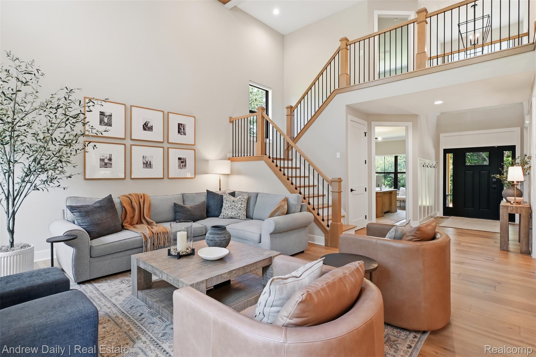 4661 Spears Road Pinckney, MI 48169 - Photo 14 of 56 Spacious living room featuring high ceilings, light wood-finish flooring, and a prominent wood staircase with black iron balusters