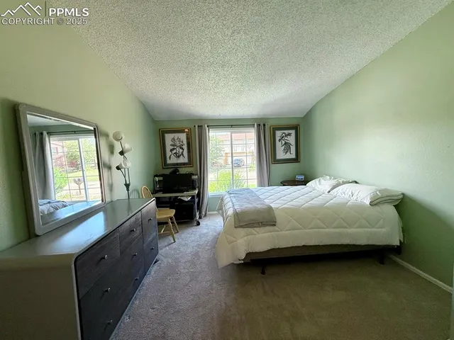 a bedroom with a bed a table and a dresser next to a window