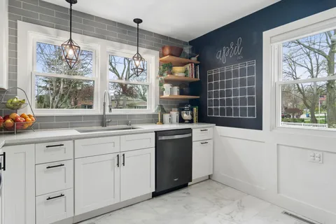 a kitchen with white cabinets and window