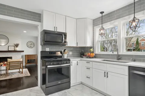 a kitchen with granite countertop a stove a sink and a microwave
