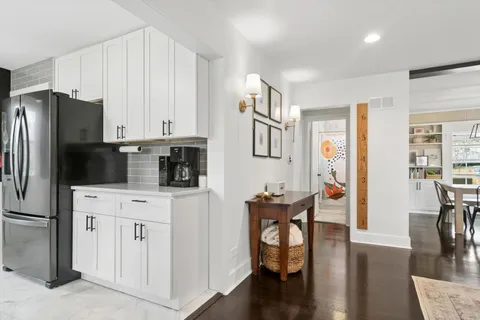 a kitchen with stainless steel appliances a microwave a stove a refrigerator a table and chairs