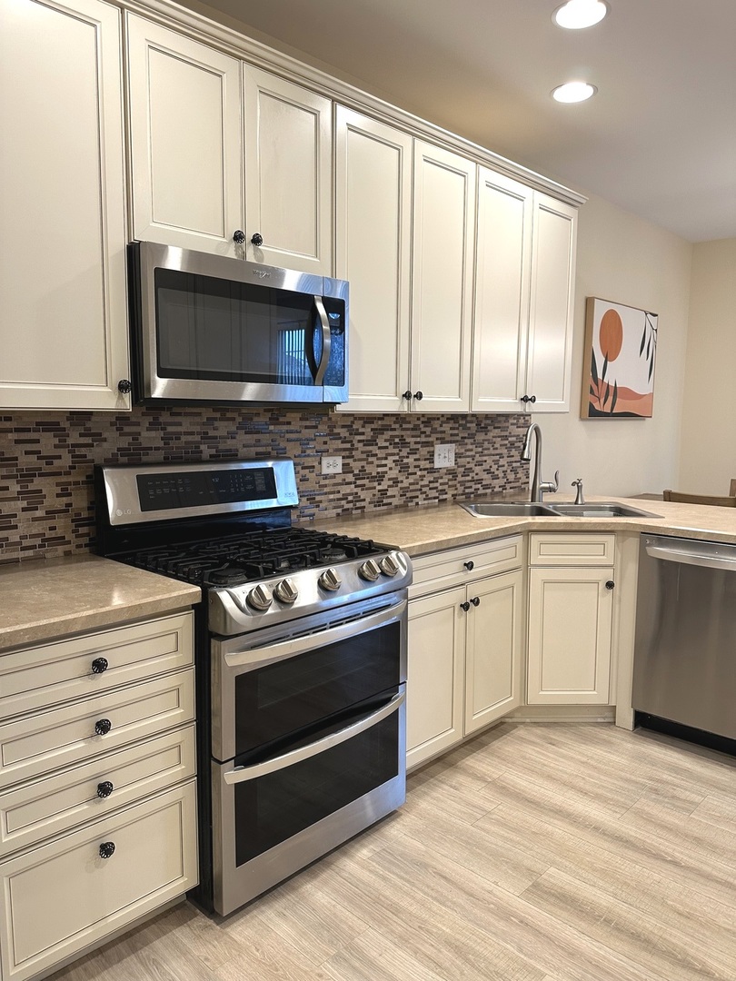 5102 Monroe Street Matteson, IL 60443 - Photo 24 of 54 a kitchen with stainless steel appliances white cabinets and a stove top oven