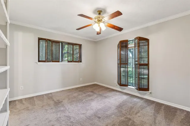 an empty room with chandelier fan and windows