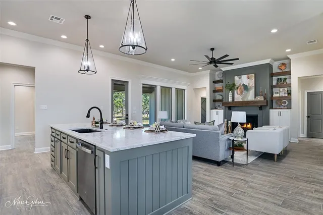 a kitchen with stainless steel appliances granite countertop a stove a sink dishwasher and a dining table with wooden floor