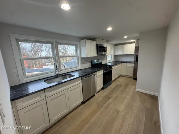 a large kitchen with a large counter top a sink a window and stainless steel appliances