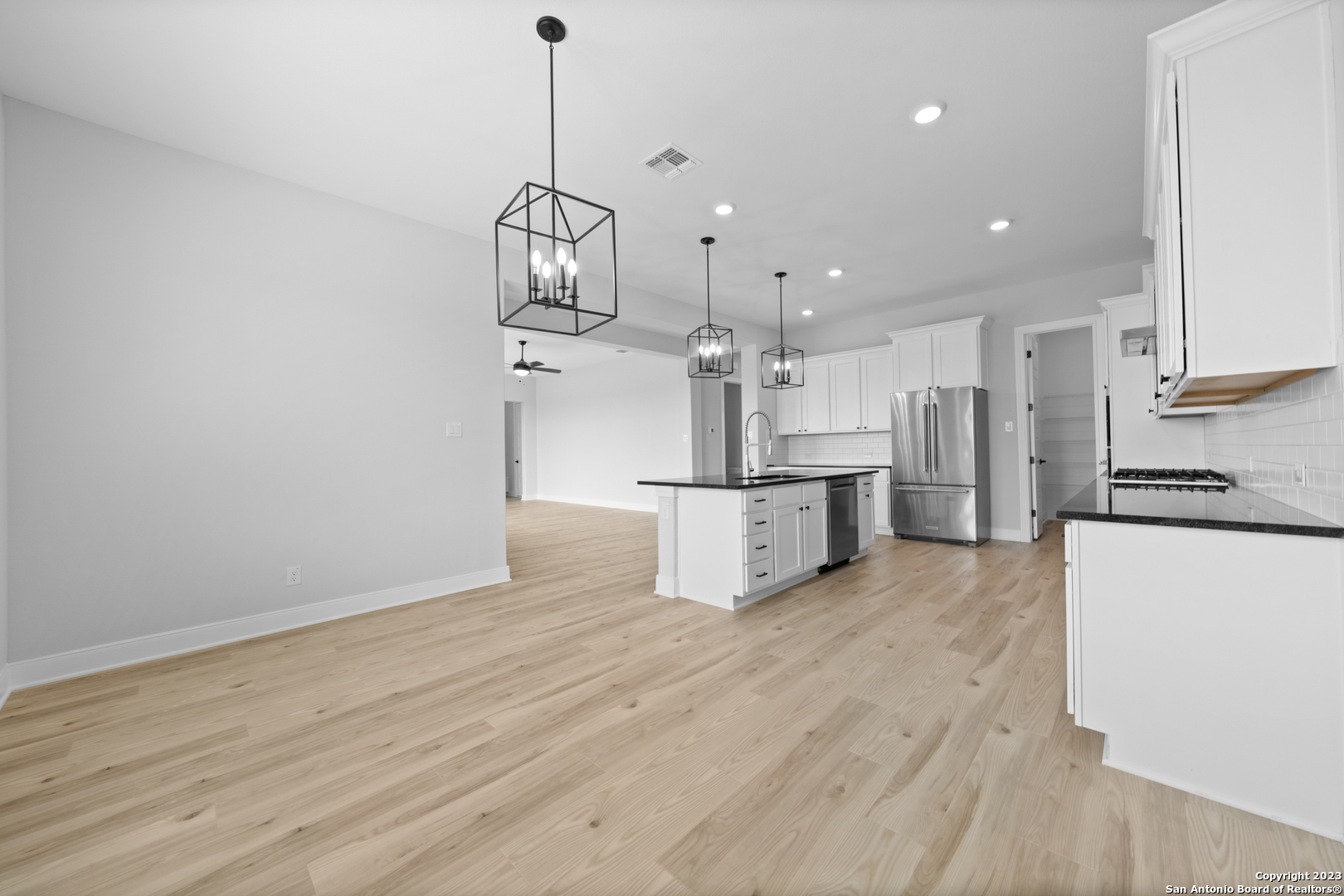 174 Azalea Alley Castroville, TX 78009 - Photo 9 of 22 a view of a kitchen with stainless steel appliances granite countertop a refrigerator a stove and white cabinets with wooden floor