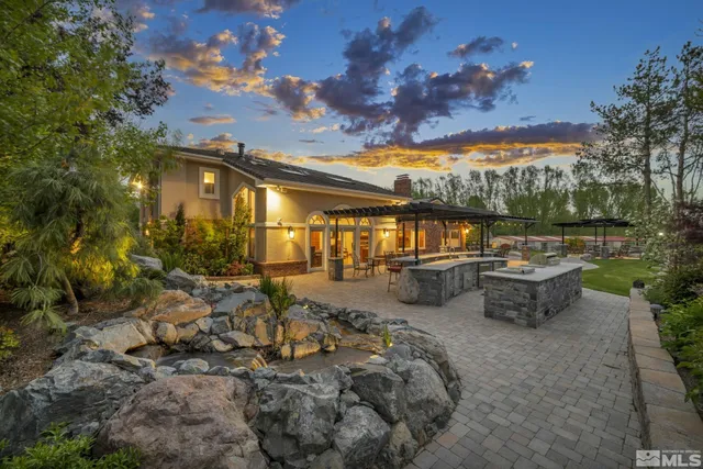 a view of a patio with table and chairs under an umbrella with a barbeque
