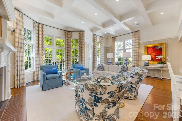 a living room with furniture large windows and wooden floor