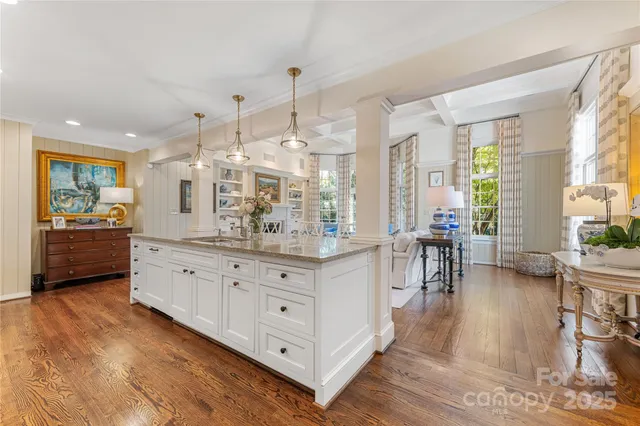a large white kitchen with granite countertop a large counter top and sink