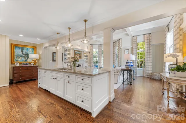 a large white kitchen with granite countertop a large counter top and sink