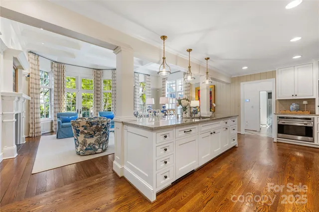 a living room with furniture large window and wooden floor