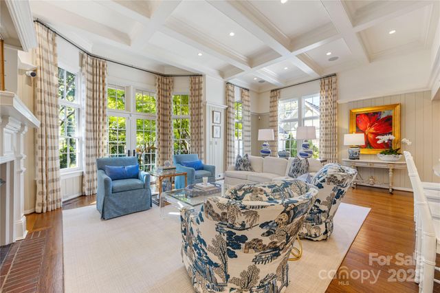 a living room with furniture large windows and wooden floor