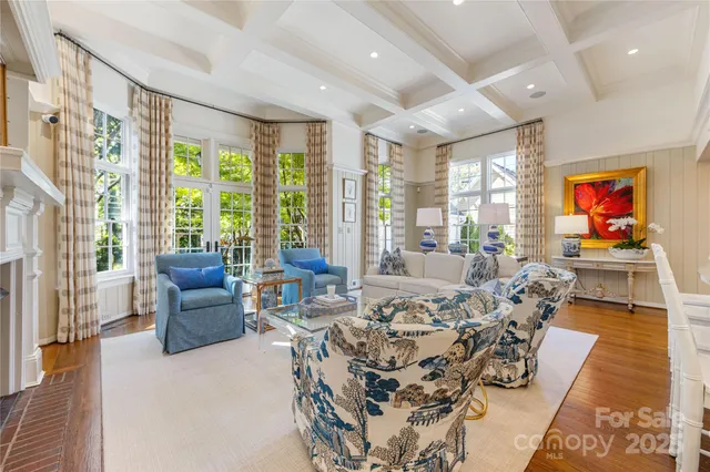 a living room with furniture large windows and wooden floor