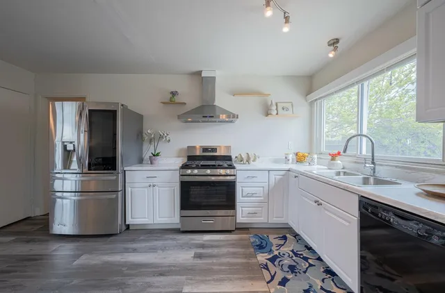 a kitchen with stainless steel appliances a sink cabinets and wooden floor