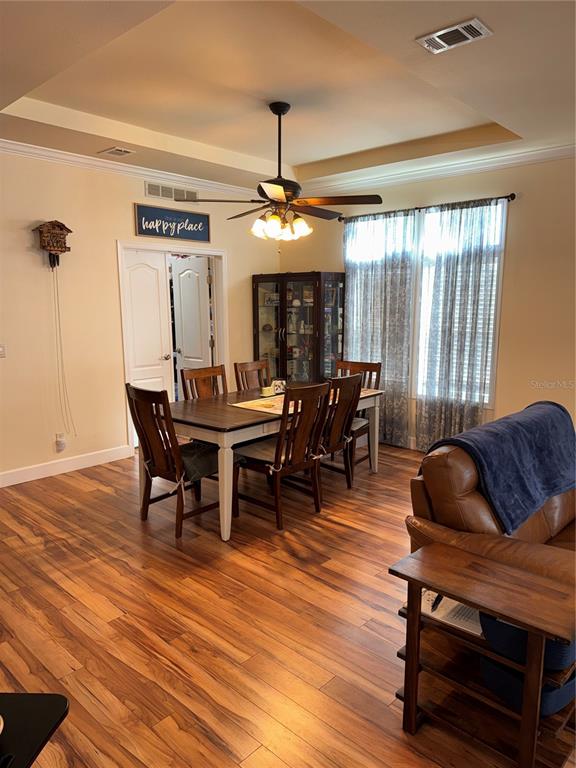 20732 South Grove Loop, Unit 630 Lutz, FL 33558 - Photo 4 of 28 a dining room with wooden floor a chandelier a glass table and chairs