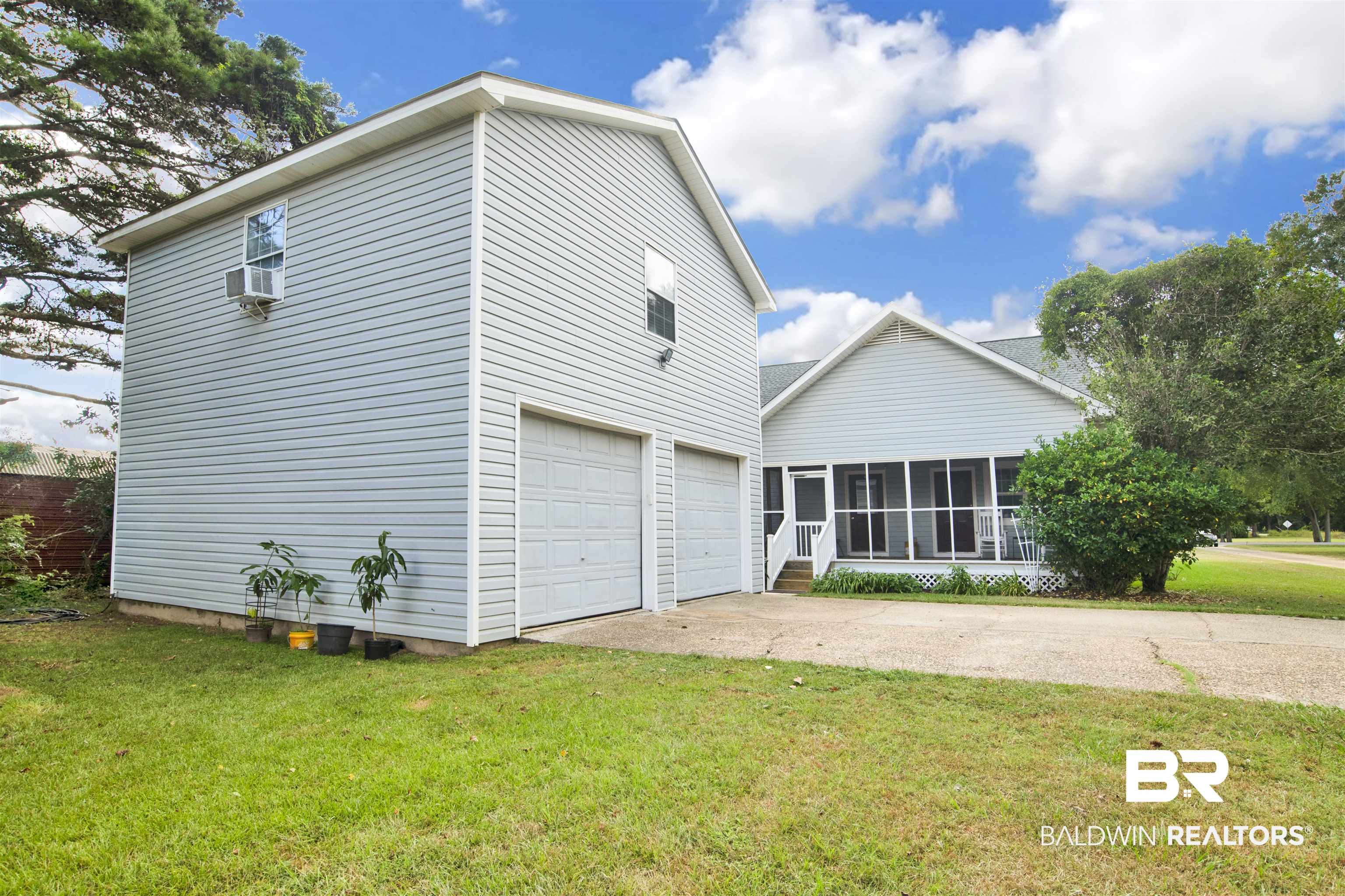 25700 Austin Road Daphne, AL 36526 - Photo 34 of 36 Rear view of house with a sunroom, driveway, a lawn, and a garage