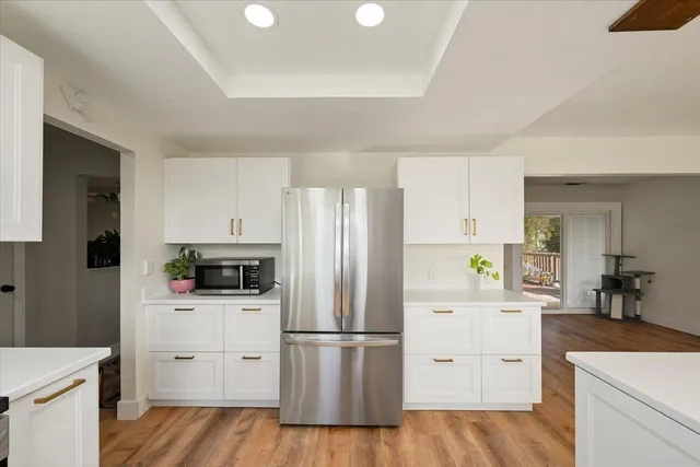 a kitchen with white cabinets white stainless steel appliances and wooden floor