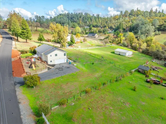 a view of a house with a yard and table and chairs under an umbrella
