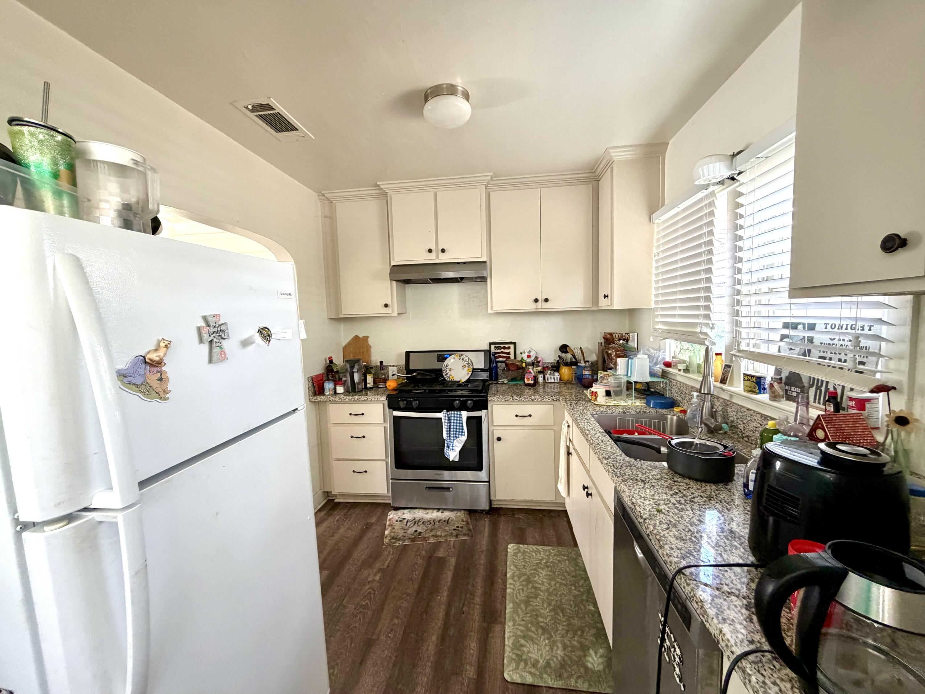 200 North B Street Exeter, CA 93221 - Photo 14 of 20 a kitchen with a refrigerator a stove a sink dishwasher and white cabinets with wooden floor