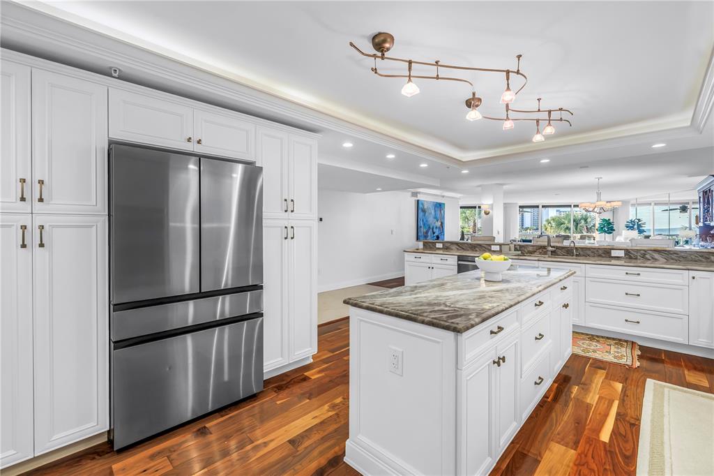 6650 Sunset Way, Unit 207 St. Pete Beach, FL 33706 - Photo 8 of 57 a kitchen with stainless steel appliances granite countertop a refrigerator a sink dishwasher and white cabinets with wooden floor