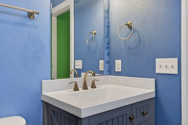 a bathroom with a granite countertop sink and a toilet
