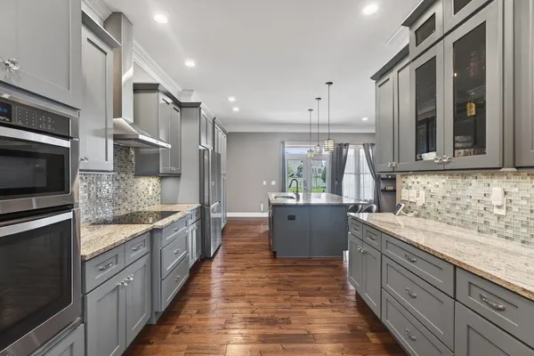 a large kitchen with stainless steel appliances granite countertop a lot of counter space and wooden floor