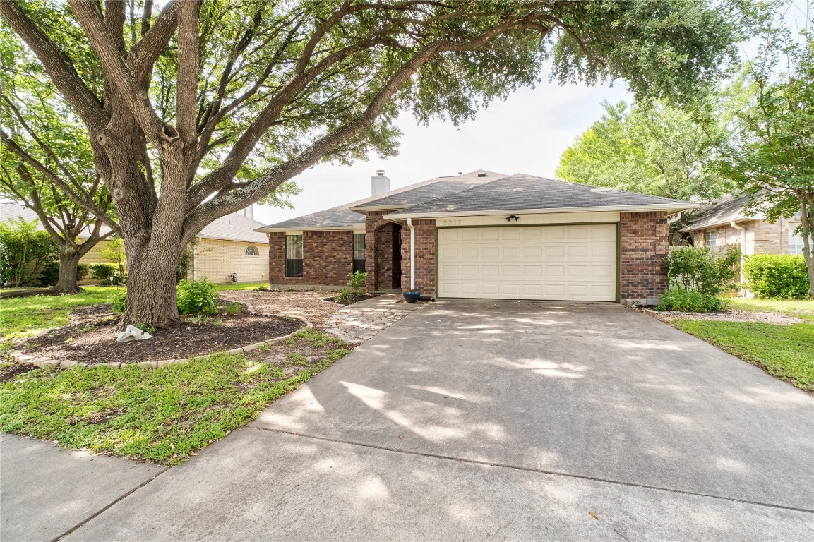 2317 Sycamore Trail Round Rock, TX 78664 - Photo 3 of 31 a front view of a house with a garden and trees