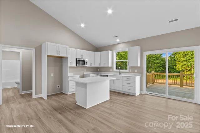 a kitchen with white cabinets and wooden floor