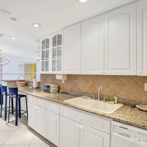 a kitchen with granite countertop white cabinets and sink