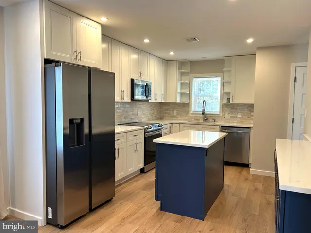 a kitchen with stainless steel appliances granite countertop a refrigerator a sink and a stove