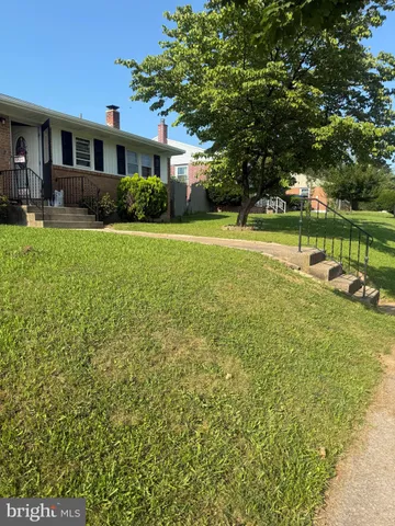 a view of house in front of a big yard with large trees