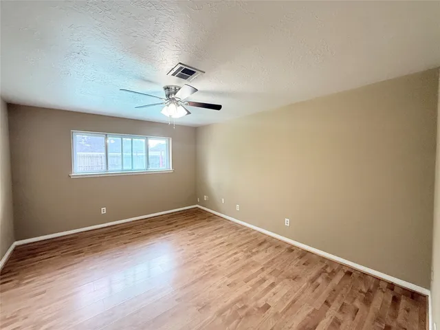an empty room with wooden floor and fan
