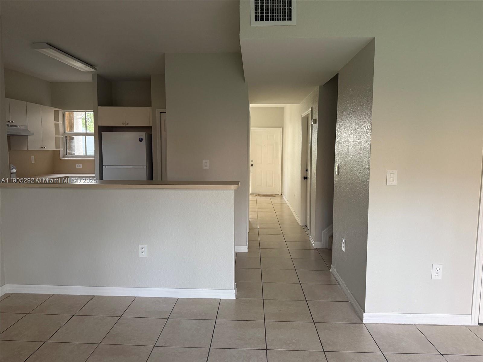 656 Southwest 11th Street, Unit 656 Florida City, FL 33034 - Photo 3 of 18 a view of a refrigerator in kitchen and an empty room