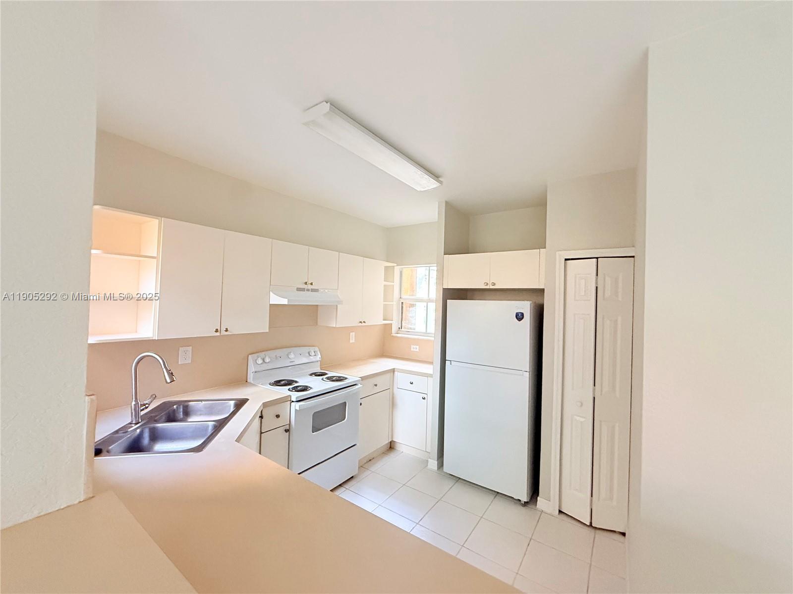 656 Southwest 11th Street, Unit 656 Florida City, FL 33034 - Photo 7 of 18 a kitchen with a refrigerator a stove a sink a washer and dryer with wooden floor