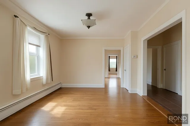 a view of an empty room with window and wooden floor