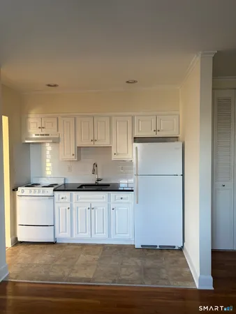 a kitchen with granite countertop white cabinets and white appliances