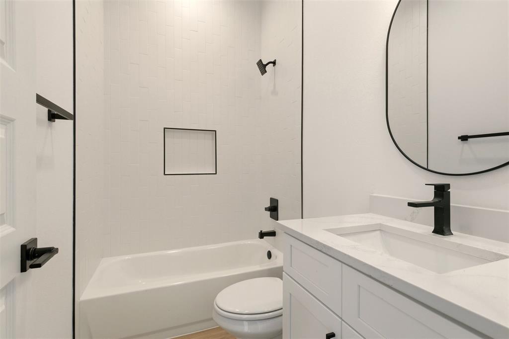 8902 Lowell Street Rowlett, TX 75089 - Photo 27 of 32 Bathroom featuring a white vanity with an integrated sink, black faucet, and an oval mirror
